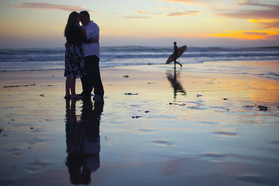 The couple kiss as a Santa Cruz surfer walks by on the State Beach.