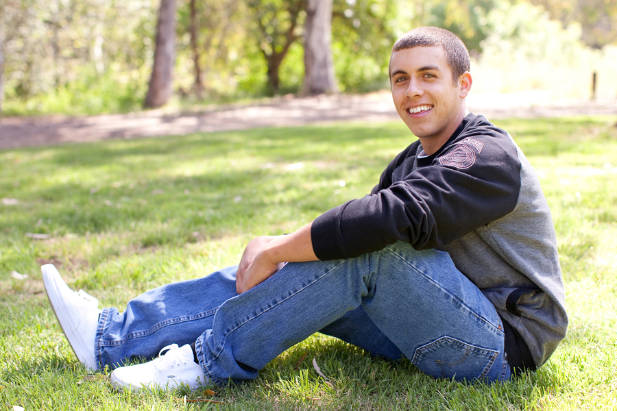Tyler hangs out on the grass for his senior portraits at a park in Gilroy.