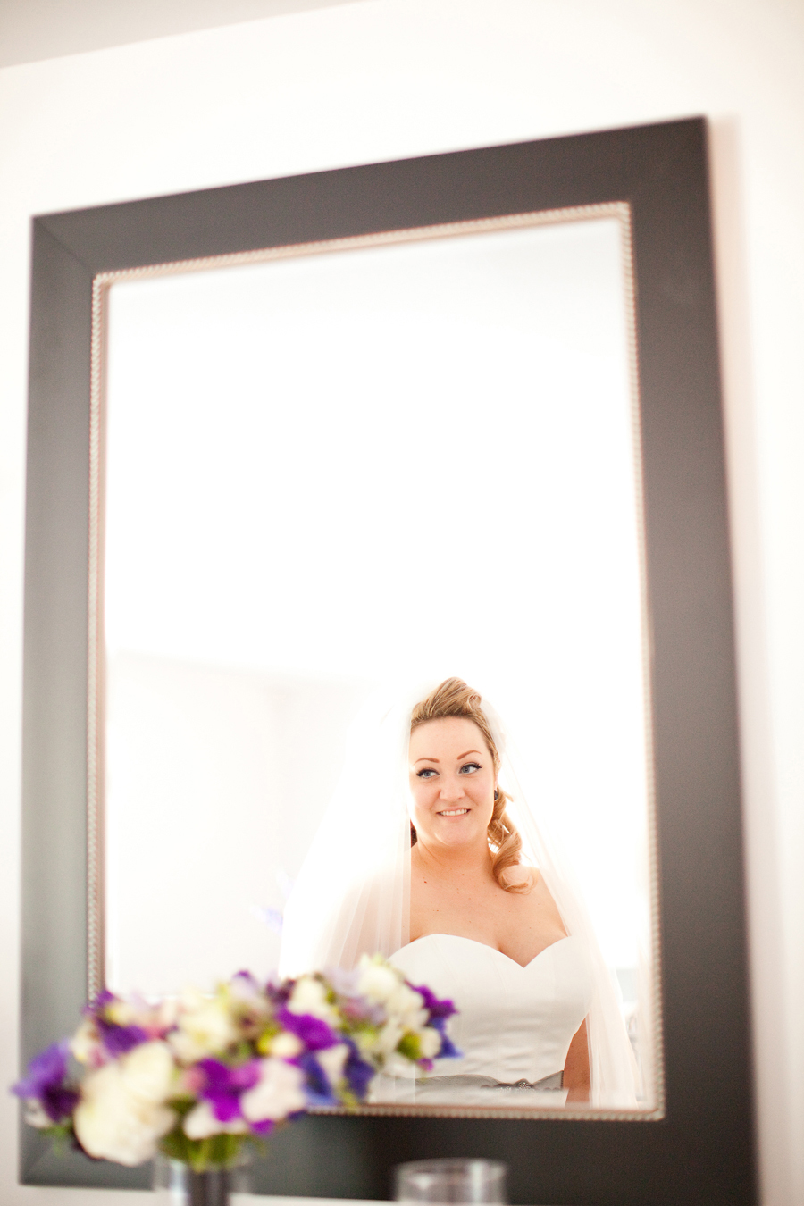 The bride looks in the mirror at the Willow Heights Mansion.