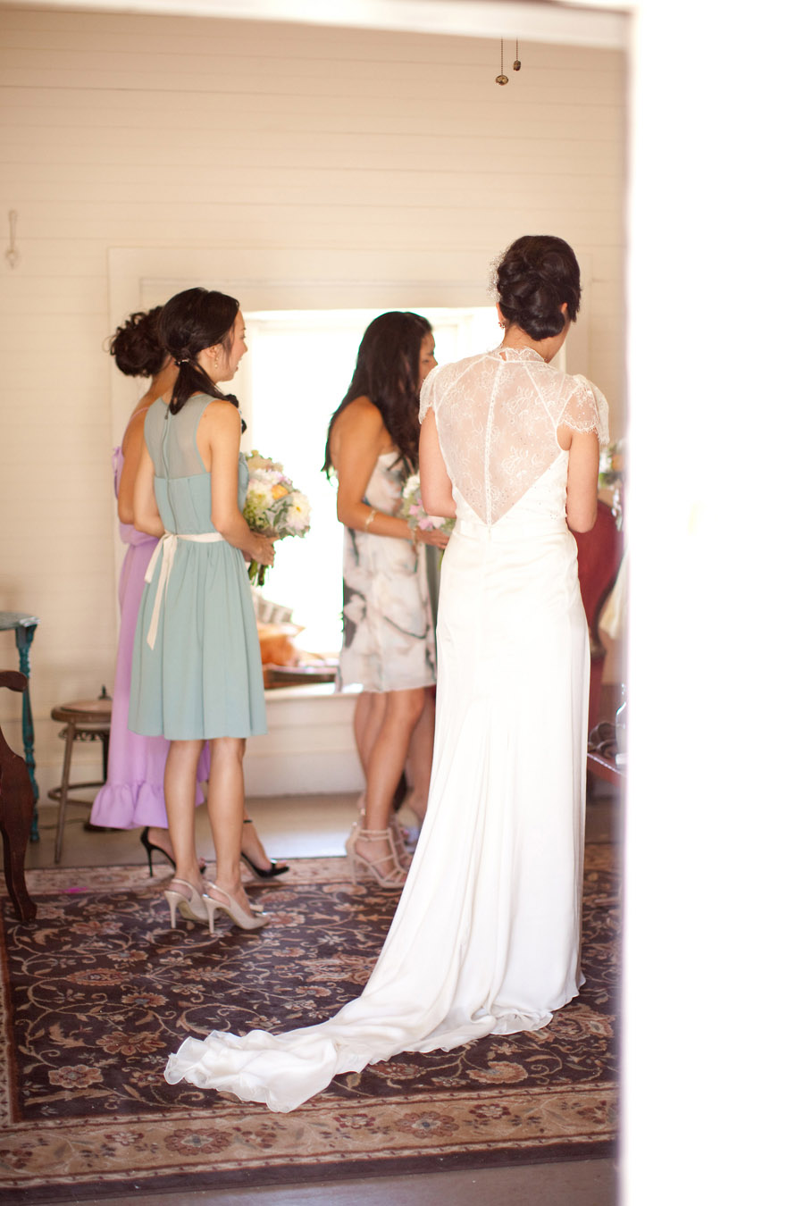 The brides elegant gown as she talks to her bridesmaids at Santa Margarita Ranch.