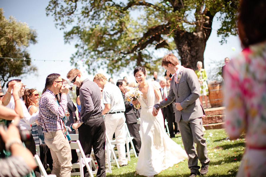 The guests throw puff balls at the couple as they walk down the aisle.