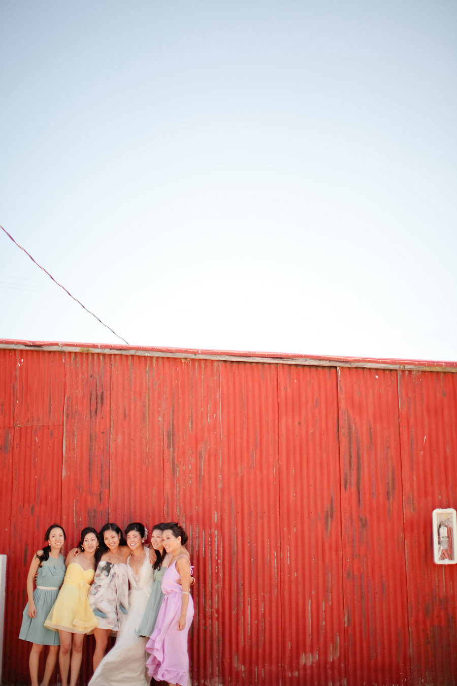 The bridal party takes pictures in front of the red barn at Santa Margarita Ranch.
