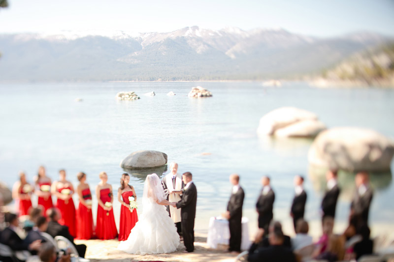 Snowcapped mountains and Lake Tahoe behind the bride and groom as they get married.