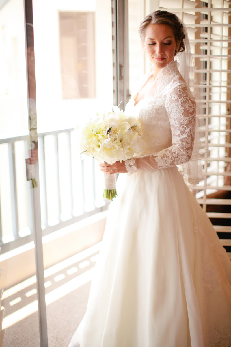 The bride stands in front of the window before she leaves to her Monterey wedding.