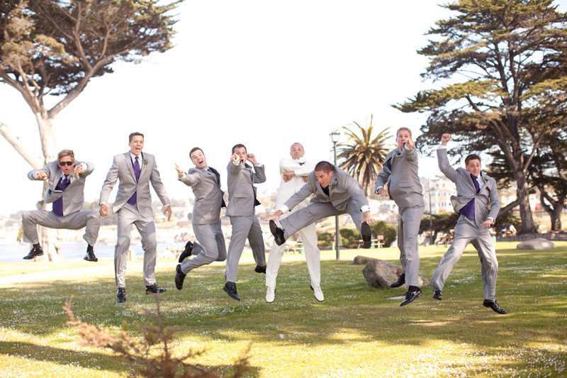 The groom and groomsman jump in the air for a picture at Lover's Point in Monterey.