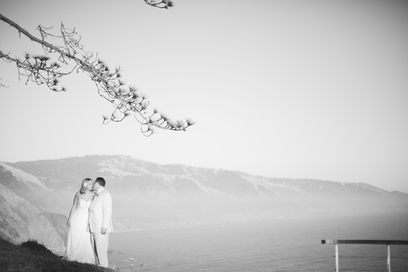 The bride and groom kiss while overlooking the ocean from Point 16 in BIg Sur.