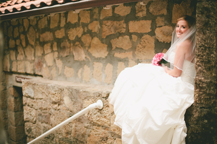 Bride sits on ledge at the winery.